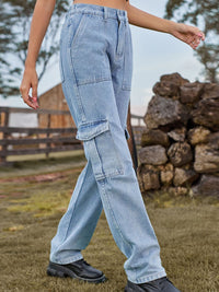 Person wearing light blue cargo jeans in an outdoor setting with a wooden fence and stone wall.