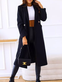 Person wearing a black coat, white top, brown skirt, and holding a black handbag with a gold logo.