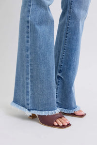 Close-up of blue jeans with ruffled hem on a light gray background