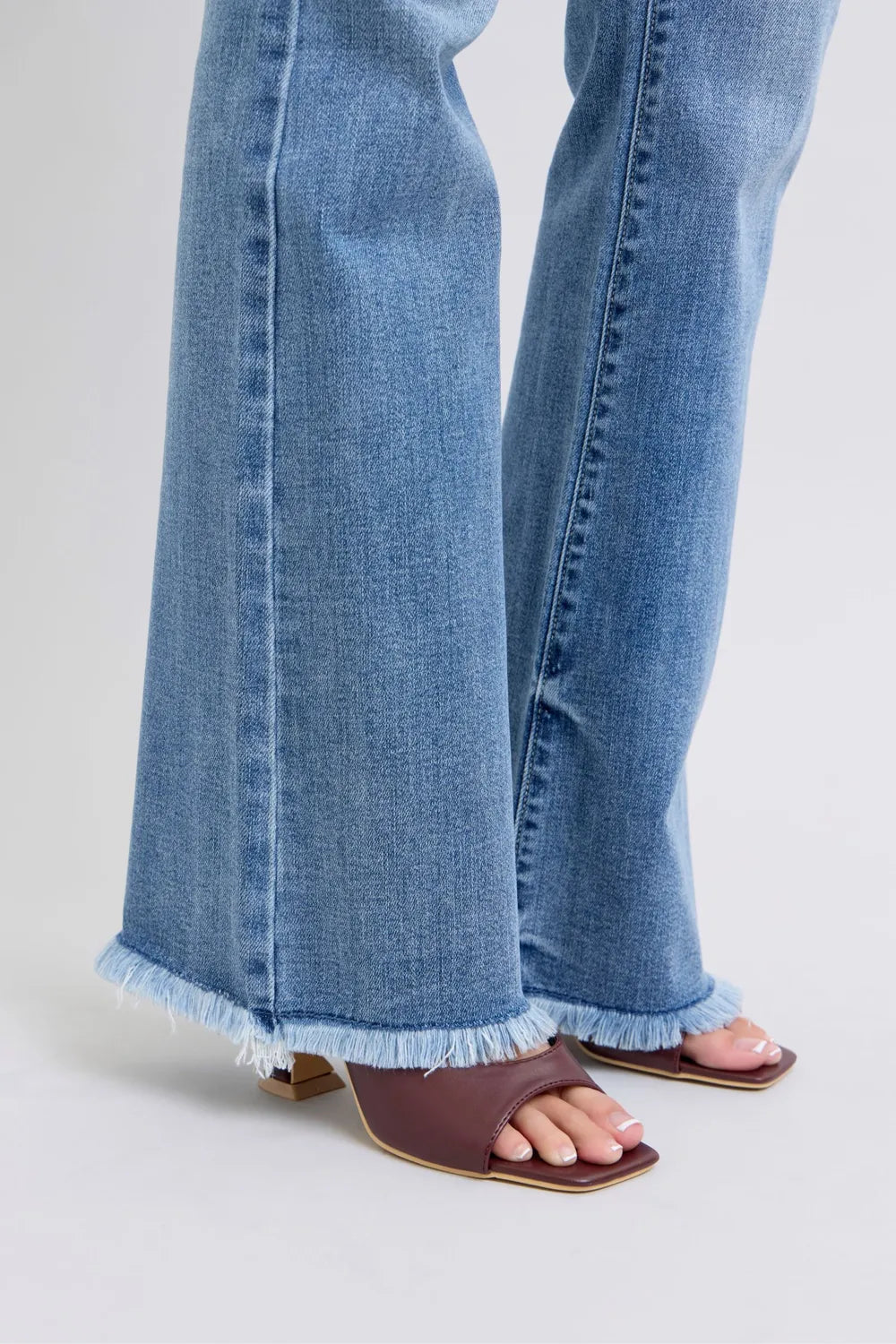 Close-up of blue jeans with ruffled hem on a light gray background