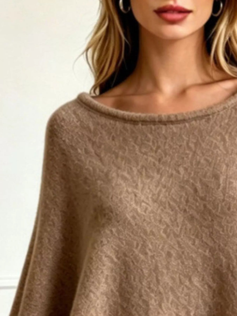 A close-up of a woman wearing a soft, textured knit poncho sweater in a warm taupe-brown color.