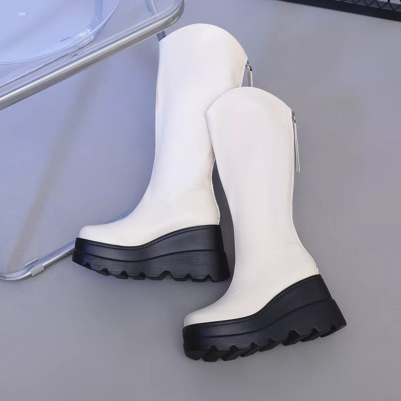 White knee-high boots with black soles on a gray surface