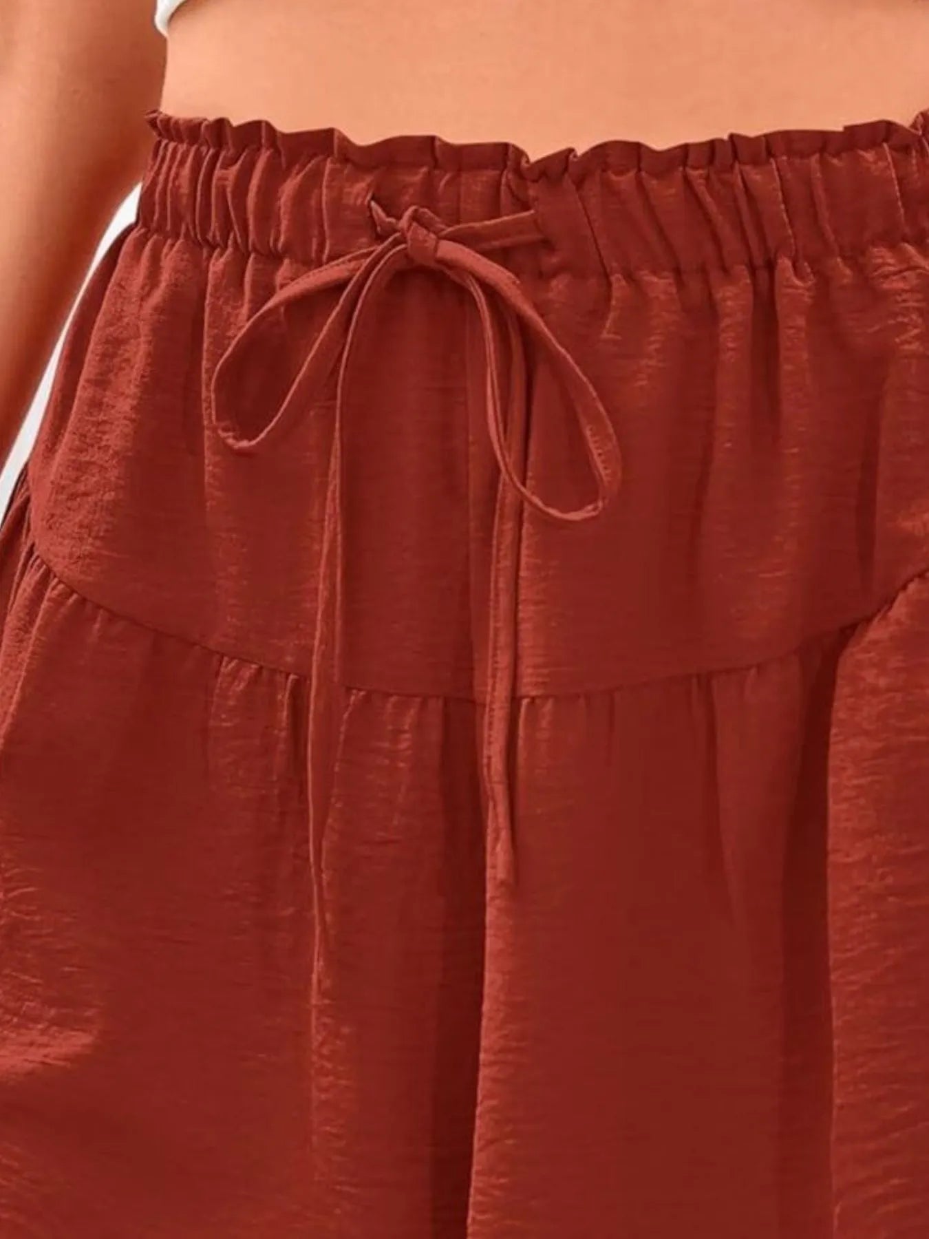 Close-up of a rust-colored skirt with a tie waist.
