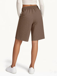 Brown shorts worn by a person on a white background