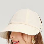 Close-up of a person wearing a beige bucket hat with a plain background