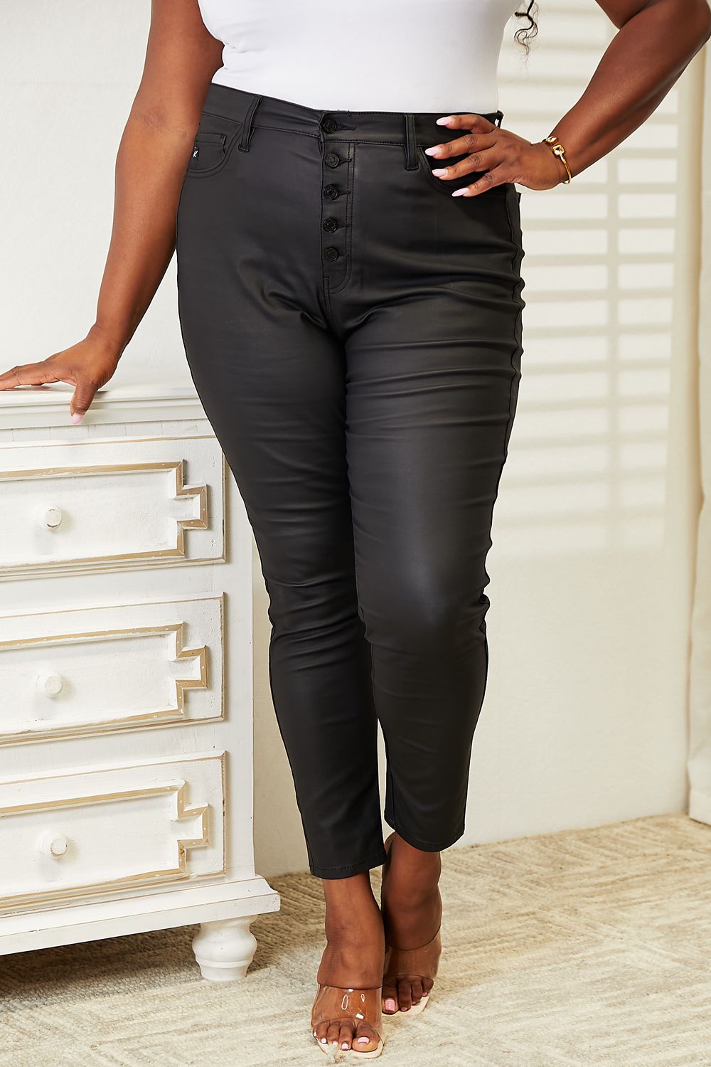 Person wearing black pants standing next to a white dresser.