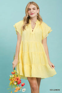 Woman wearing a yellow dress holding flowers against a light blue background