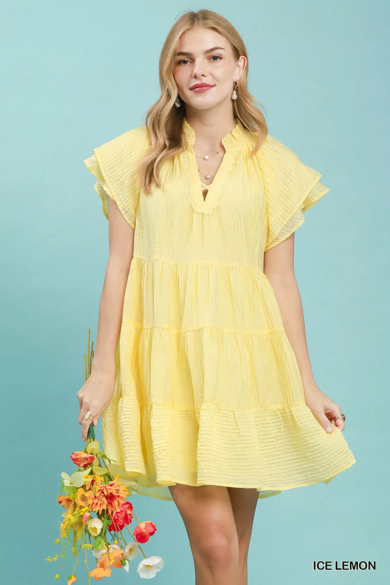 Woman wearing a yellow dress holding flowers against a light blue background