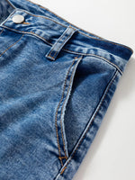 Close-up of blue denim fabric with a button on a white background