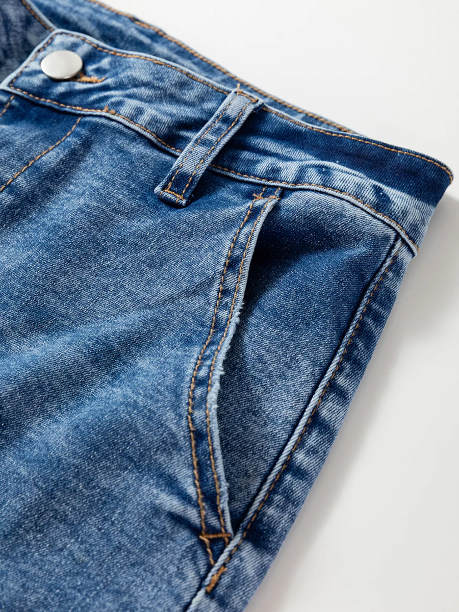 Close-up of blue denim fabric with a button on a white background