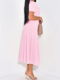 Person wearing a pink pleated skirt and top on a white background