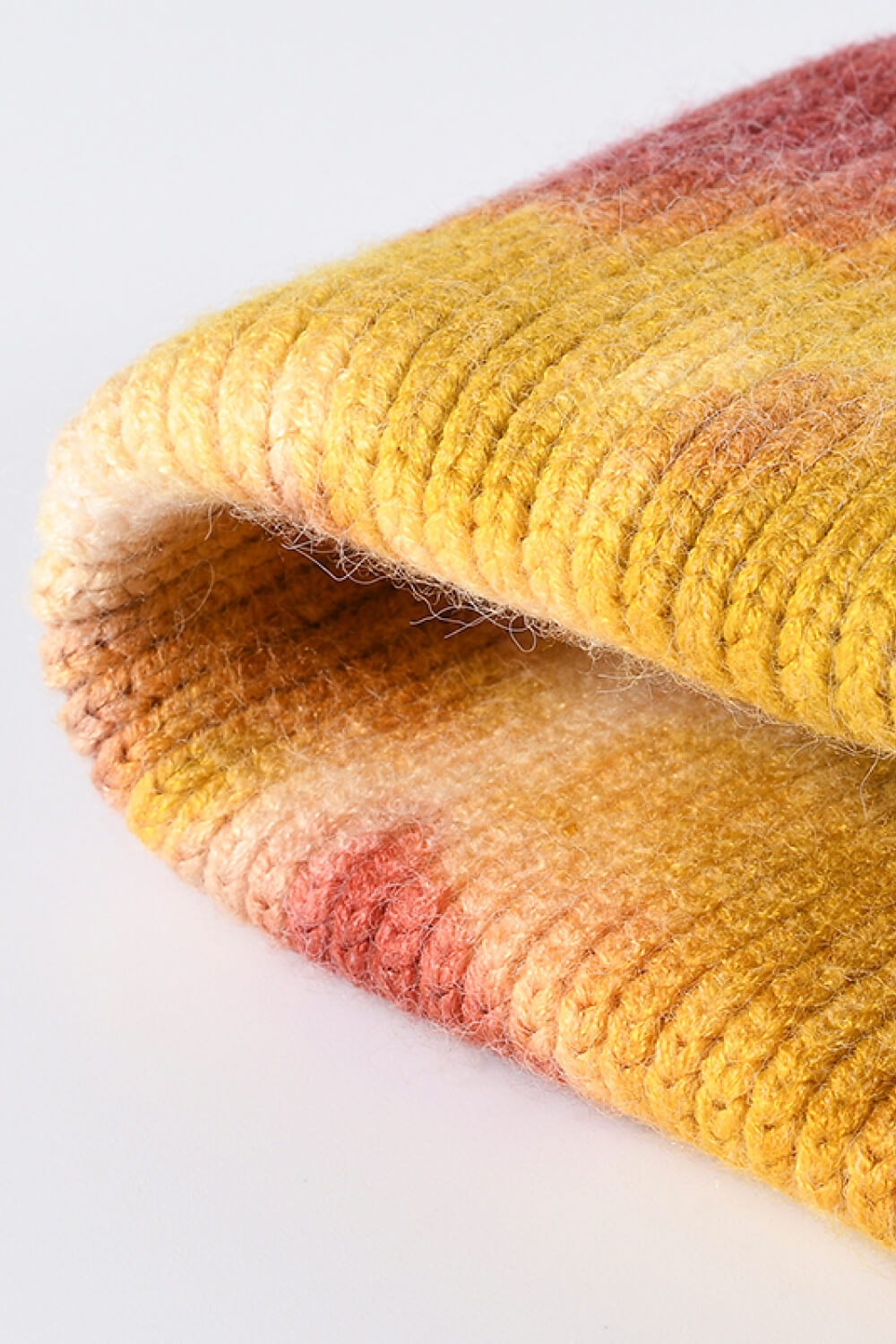 Close-up of a textured fabric with yellow and pink gradient on a white background