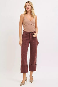 Woman wearing a brown sleeveless top and maroon pants on a white background
