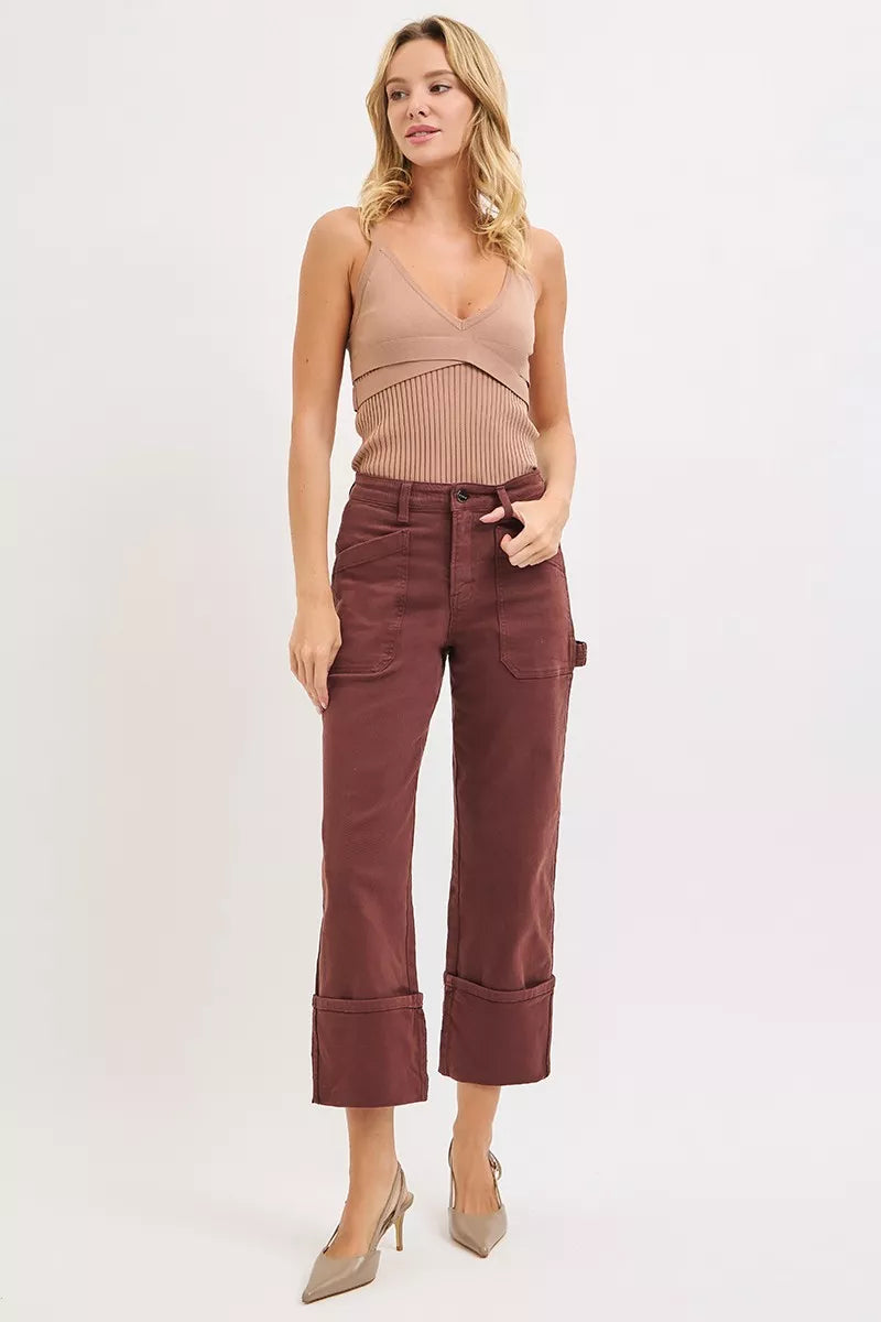Woman wearing a brown sleeveless top and maroon pants on a white background