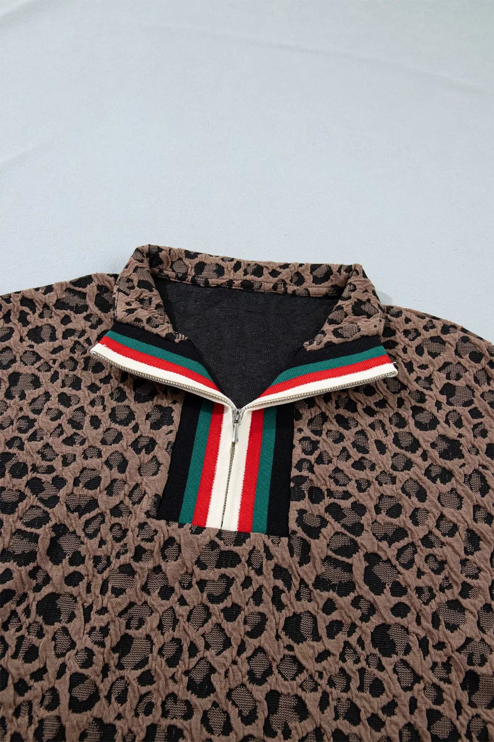 Leopard print jacket with a colorful zipper on a light gray background