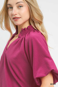 Woman wearing a magenta blouse with a plain background