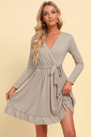 Woman wearing a gray wrap dress with a beige background