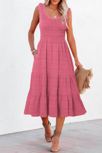 Woman wearing a pink dress holding a straw hat against a white background