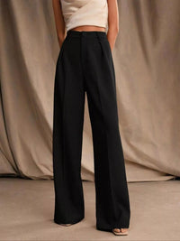 Person wearing black wide-leg pants against a beige curtain background