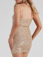 A woman wearing a sleeveless, bodycon mini dress covered in shimmering rose gold sequins, shown from a rear three-quarter angle against a light gray studio background.