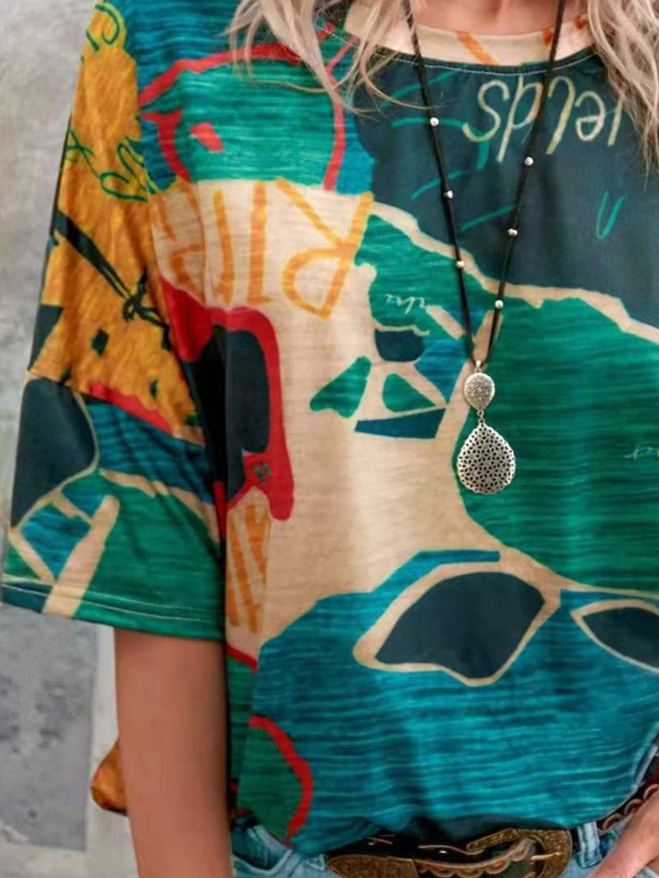 Person wearing a colorful dress with abstract patterns and a necklace.