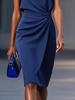Woman wearing a blue dress holding a blue clutch against a neutral background