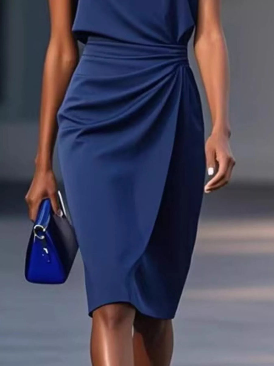 Woman wearing a blue dress holding a blue clutch against a neutral background