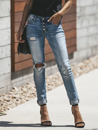 Person wearing ripped blue jeans with a blurred background