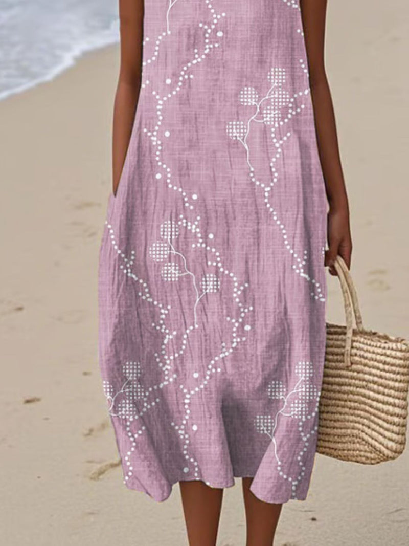 Person wearing a pink dress with white floral patterns on a beach.