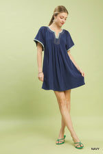 Woman wearing a navy dress with white trim on a light green background