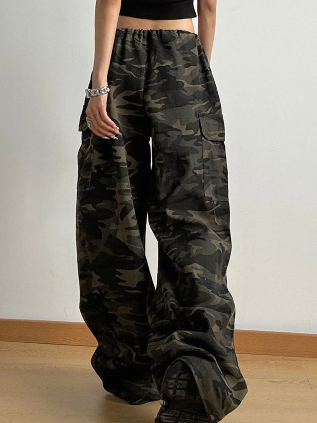 Camouflage pants worn by a person on a plain background