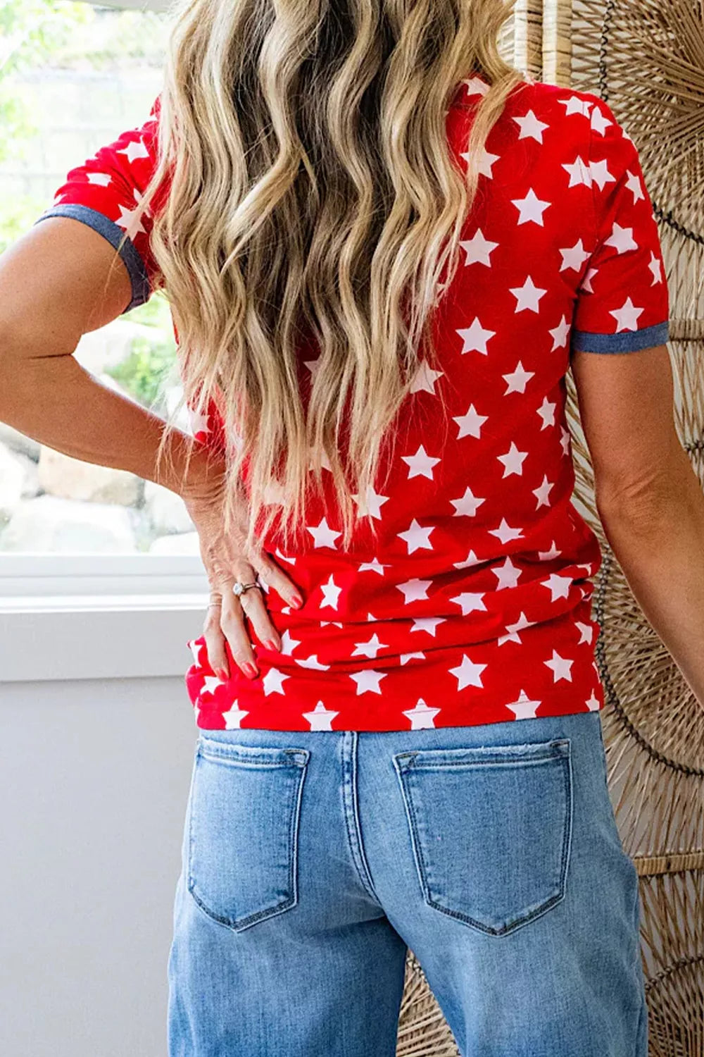 Person wearing a red shirt with white star pattern and blue jeans indoors.