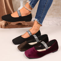 Black, brown, and purple flats with rhinestone straps on a neutral background