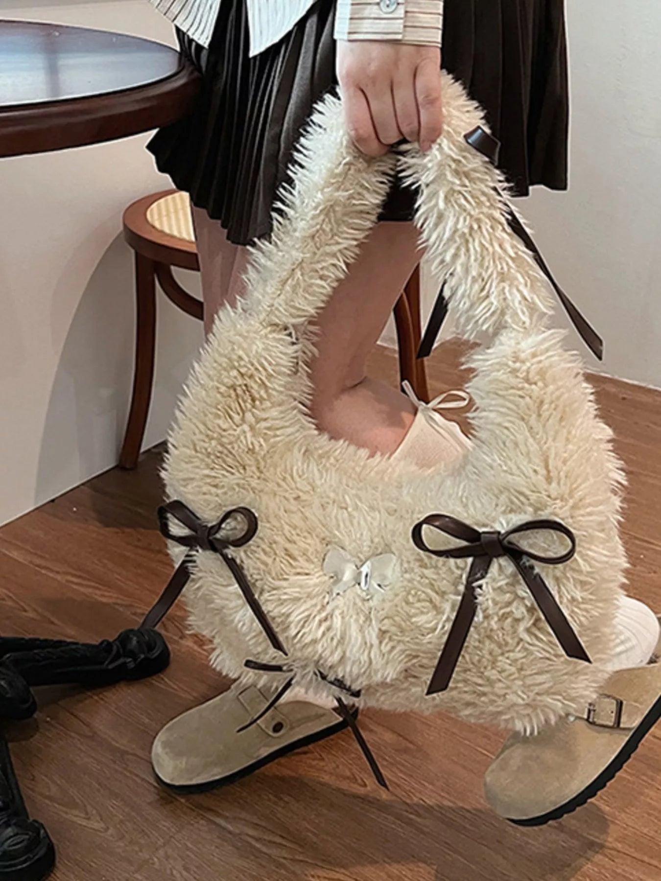 Person wearing a fluffy white boot with a bow, sitting on a chair indoors.