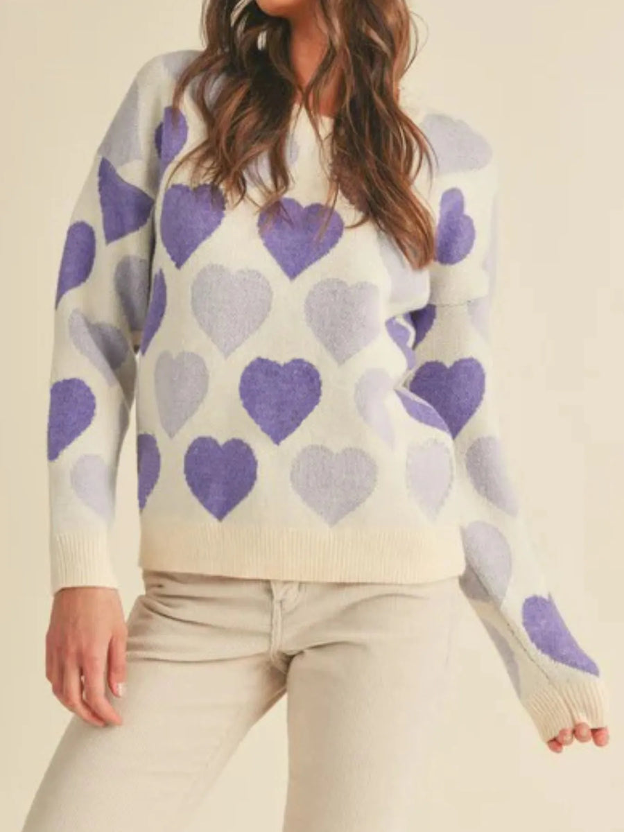 Person wearing a sweater with purple heart patterns on a beige background