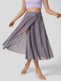 Person wearing a long, flowing purple skirt on a plain background