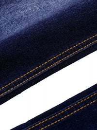 Close-up of blue denim fabric with orange stitching on a white background