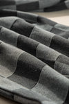 Stack of folded gray and black striped fabric on a checkered surface