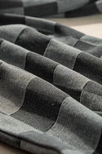 Stack of folded gray and black striped fabric on a checkered surface