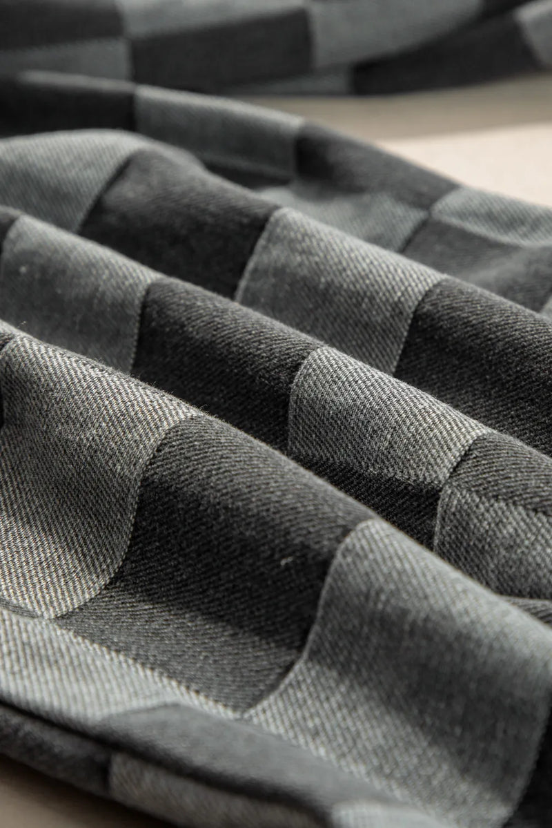 Stack of folded gray and black striped fabric on a checkered surface