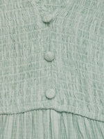 Close-up of a light green textured fabric with buttons