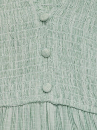 Close-up of a light green textured fabric with buttons