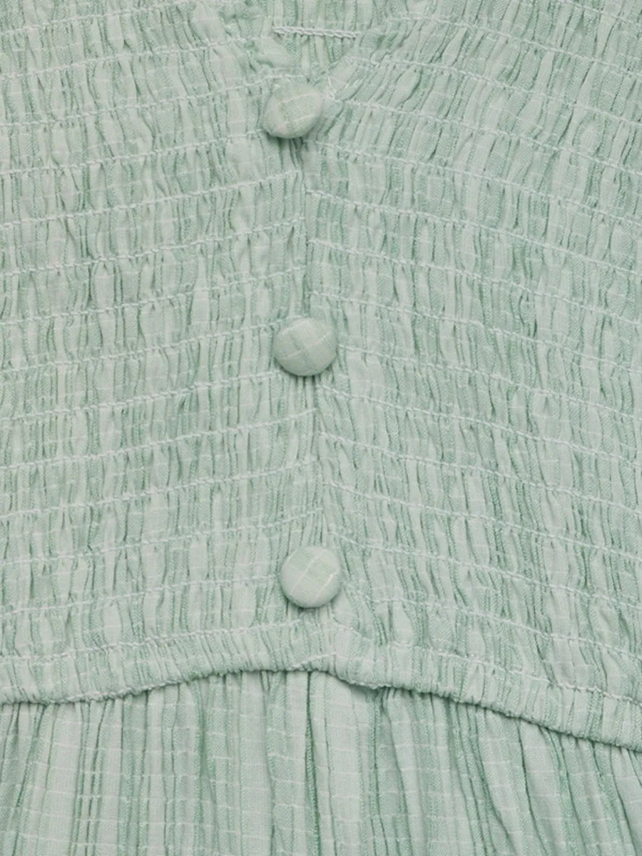 Close-up of a light green textured fabric with buttons