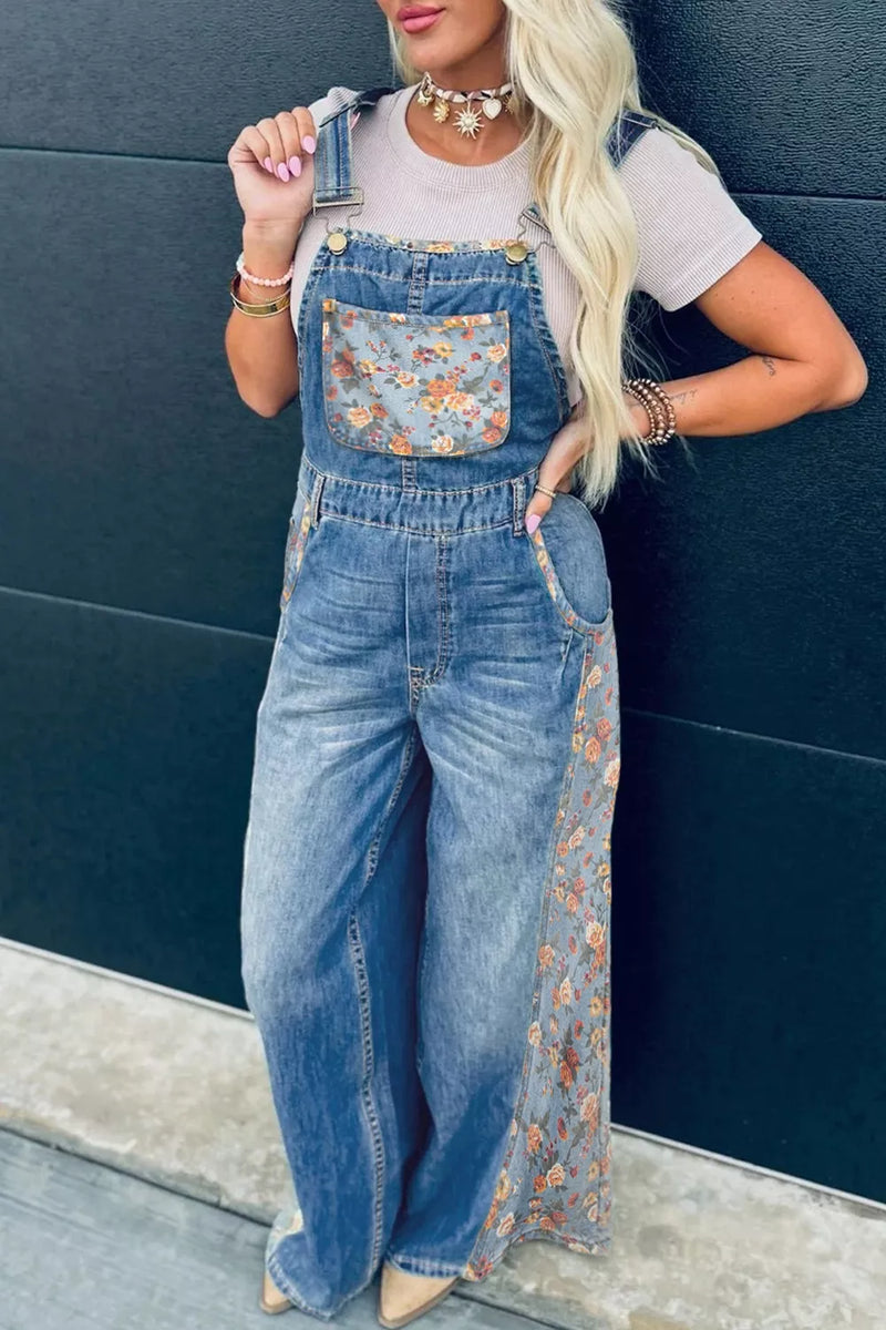 Person wearing floral denim overalls against a dark blue wall