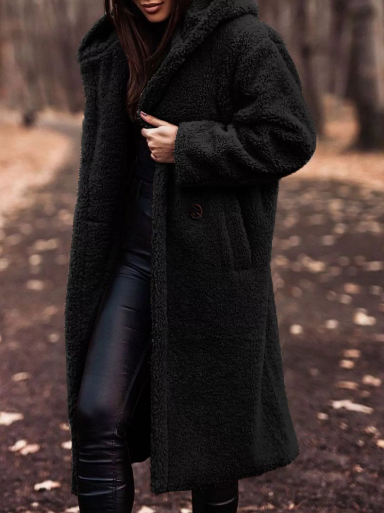 Person wearing a long dark coat in a forest setting