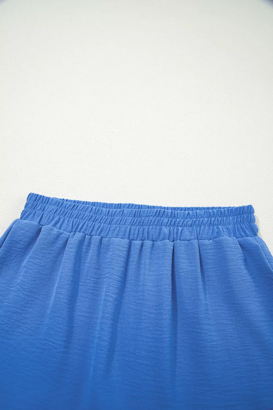 Close-up of blue shorts with an elastic waistband on a light gray background