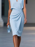 Woman wearing a light blue dress holding a matching clutch.