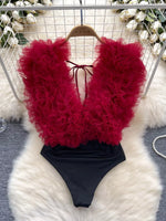 Red feathered top and black bottom swimsuit on a white fur surface.