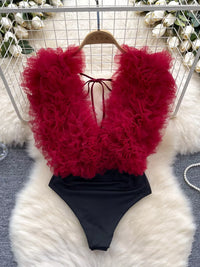 Red feathered top and black bottom swimsuit on a white fur surface.