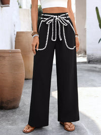 Person wearing black wide-leg pants with white trim in an outdoor setting.